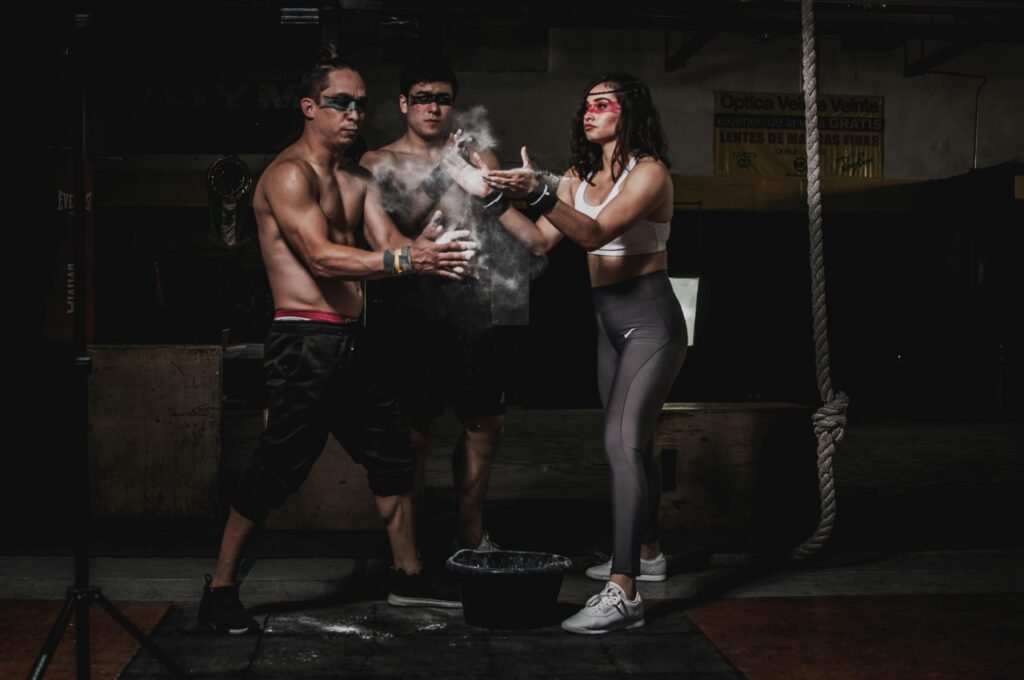 Three adults in sportswear use chalk in a gym, ready for intense workout.