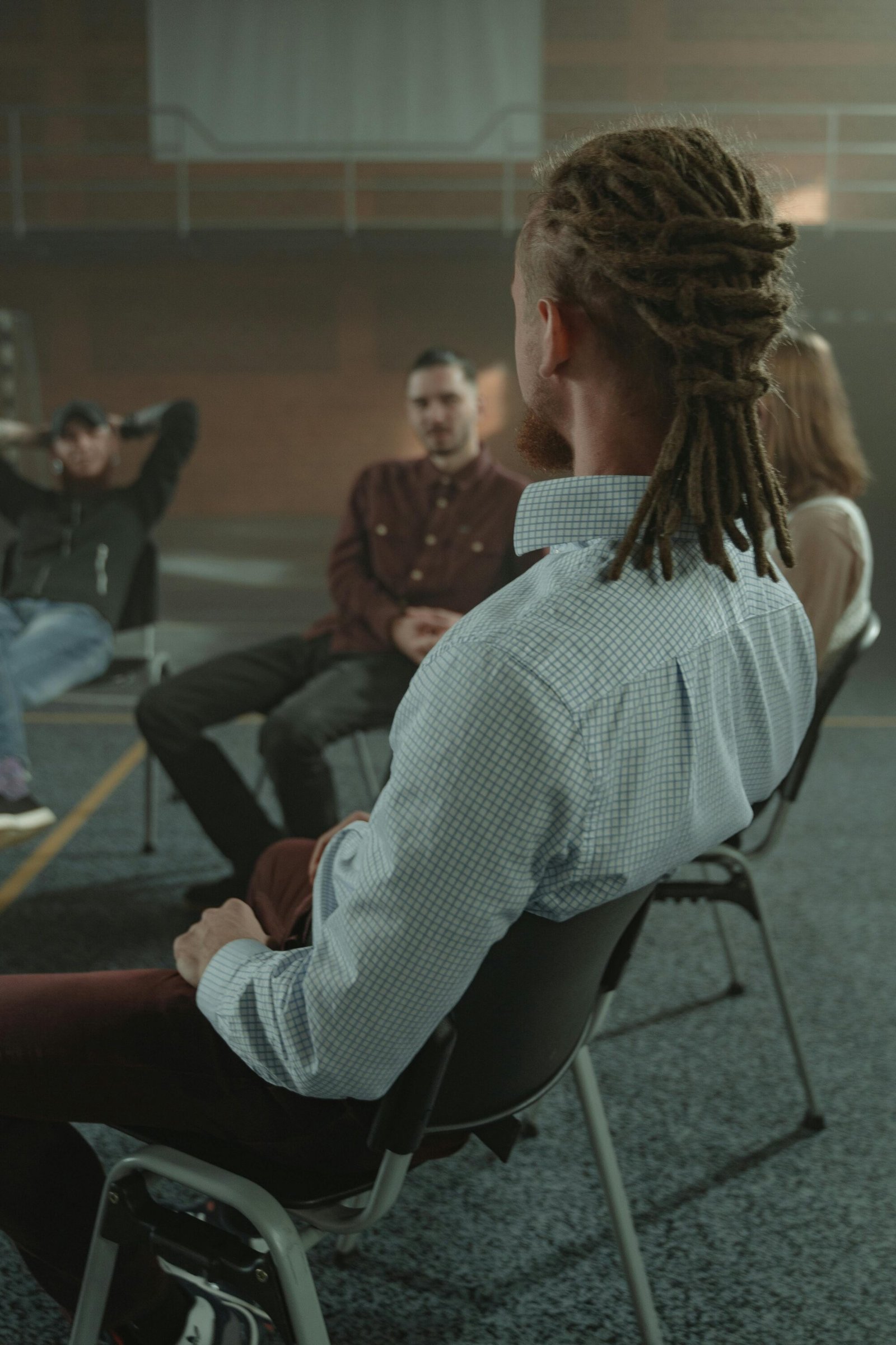 A diverse group of adults engaging in a support therapy session in an indoor setting.